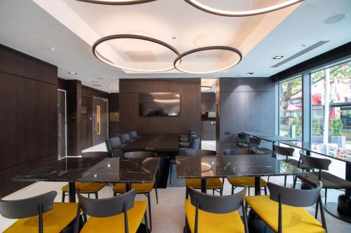 伦敦Signature London, The J Marylebone的用餐室配有黑色桌子和黄色椅子