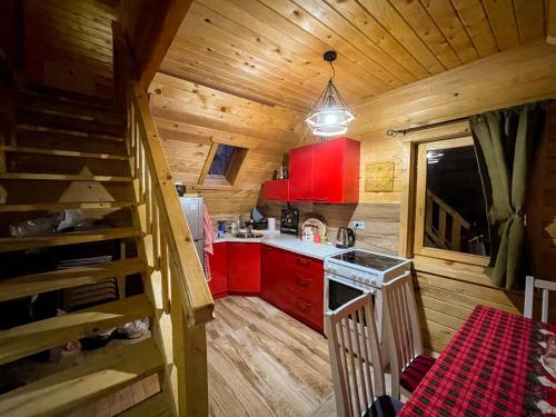 布雷佐维察Cozy Cabin in the Woods的一间厨房,内设红色橱柜和小屋内的楼梯