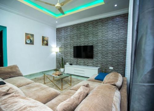 KasoaMatata Homes Airbnb的客厅设有2张棕色沙发和砖墙