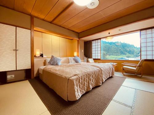 大崎市龟屋饭店的一间卧室设有一张大床和一个大窗户