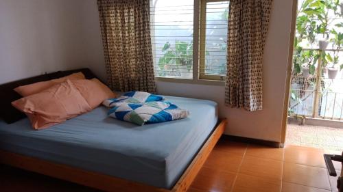 日惹Petik Merah Homestay的卧室配有带枕头的床铺和窗户。