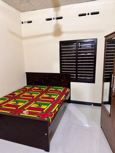 贾夫纳Jaffna Town的一间卧室配有一张带五颜六色棉被的床