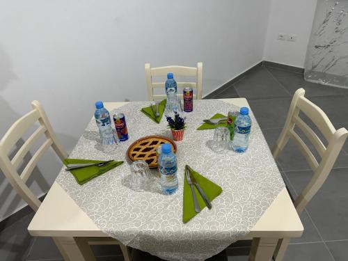 都拉斯Home Anxhelo的一张带椅子的白色桌子和瓶装水