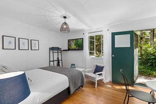 春溪Rosella's On Springbrook的卧室配有床、椅子和窗户。