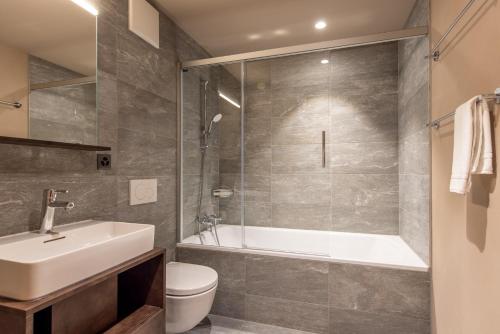 琪纳尔SWISSPEAK Resorts Zinal的带浴缸、盥洗盆和卫生间的浴室