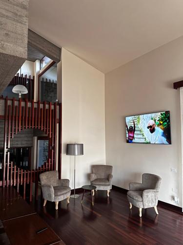 PopiglioVilla Belvedere di Popiglio的客厅配有两把椅子和墙上的电视