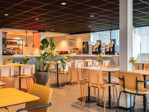 巴德胡弗多普阿姆斯特丹机场宜必思快捷酒店的自助餐厅内带桌椅的餐厅