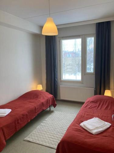 万塔Kotimaailma - Kalustettu saunallinen asunto kuudelle的一间卧室设有两张红色的床和窗户