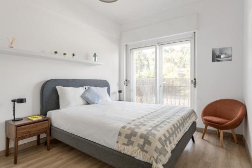 里斯本JOIVY Striking flat in Benfica的卧室配有床、椅子和窗户。