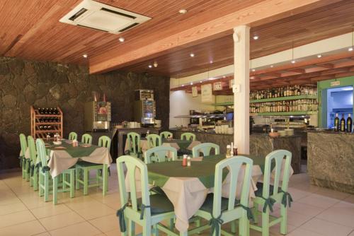 卡门港多拉多竞技场公寓酒店的一间设有绿色桌椅的餐厅和一间酒吧