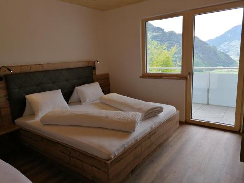海因岑贝格Montepart Zillertal的一间卧室设有一张大床和大窗户