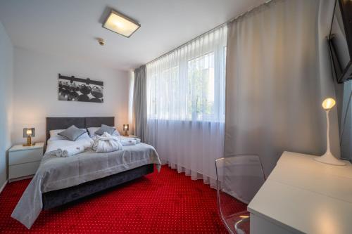 波兹南波兹南格罗马达酒店的一间卧室配有一张床,铺有红色地毯