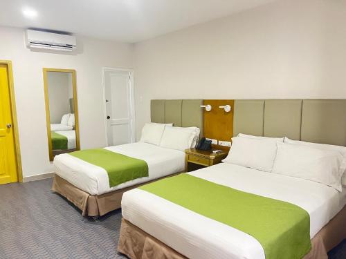 巴兰基亚Hotel American Golf的酒店客房,设有两张绿色和白色的床