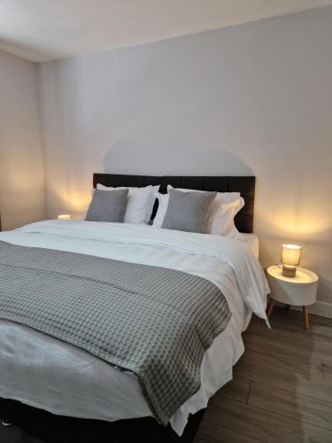 伦敦Stylish 2 bed home- short walk to Tottenham Stadium/Stations的一间卧室配有一张带两盏灯的大型白色床。
