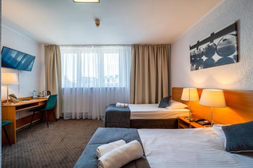 波兹南波兹南格罗马达酒店的酒店客房配有两张床和一张书桌