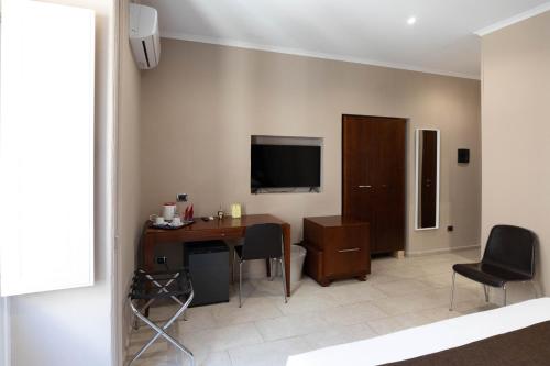 锡拉库扎埃尔多莫酒店的客房设有书桌、电视和椅子。