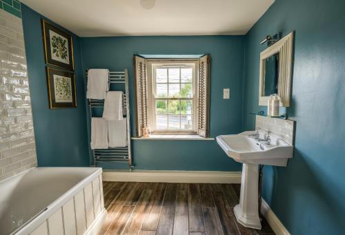 彭里斯George and Dragon Clifton的蓝色的浴室设有水槽、浴缸和窗户。