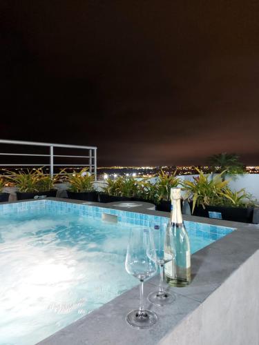 萨利纳斯Oasis Suite Salinas的两个酒杯和葡萄酒瓶坐在游泳池旁