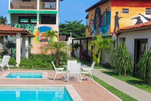 伊塔帕里卡岛维拉克鲁兹Flat - Condomínio Fechado - Frente Mar的一个带椅子和壁画的游泳池的房子