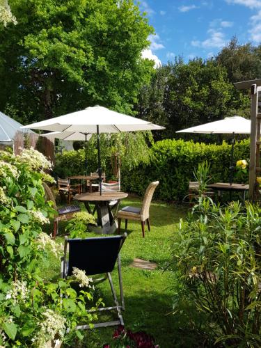 安德诺莱斯贝恩Chambres d'hôtes couleur bassin d'Arcachon的花园配有桌椅和遮阳伞