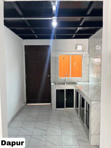 TuaranElijah’s Tiny House的一间空厨房,里面装有橙色橱柜和门