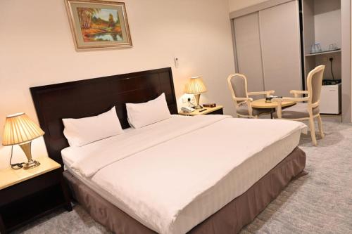 利雅德Al Furat Madayin Hotel的一间卧室配有一张大床和一张桌子及椅子