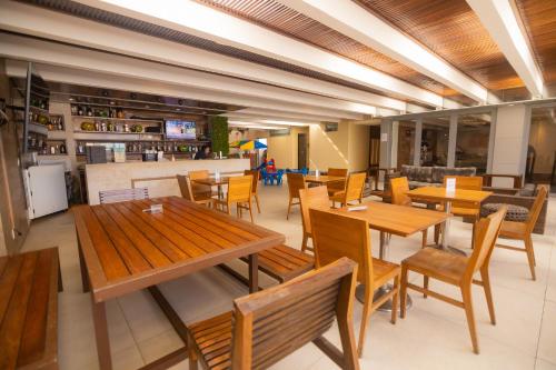 里约热内卢Riale Brisa Barra的一间带木桌椅的餐厅和一间酒吧
