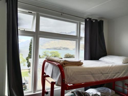 皇后镇Lakeside Backpackers的一间卧室设有一张床和一个大窗户