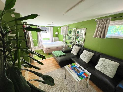 特雷勒堡Lovely cottage by the south coast的客厅设有黑色沙发和绿色的墙壁