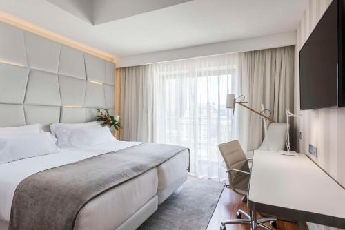 马德里马德里科隆NH系列酒店的酒店客房设有一张大床和一张书桌。