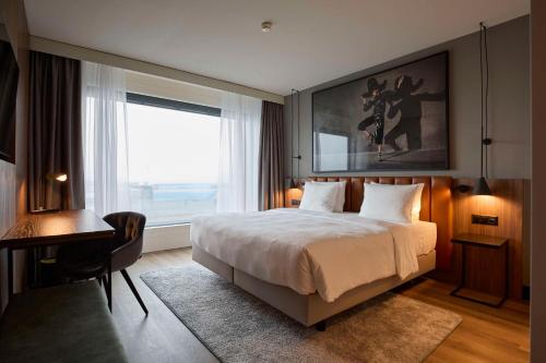 克洛滕Radisson Blu Hotel Zurich Airport的一间卧室配有一张床、一张书桌和一个窗户。