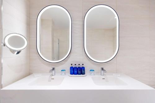 格拉斯哥格拉斯哥丽笙酒店的浴室内白色水槽上方的两面镜子