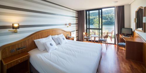 莱亚斯Laias Caldaria hotel y Balneario的酒店客房配有一张床、一张书桌和一台电视。