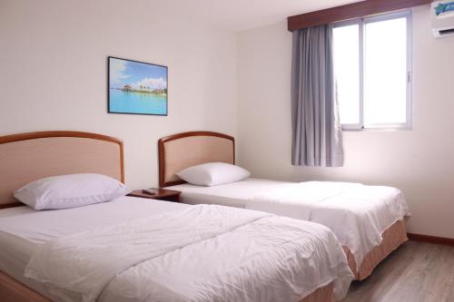 TinianTinian Lucky Home的酒店客房设有两张床和窗户。