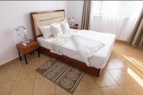 阿鲁沙Lerai X Desty的一间卧室配有一张大床和一个带灯的床头柜