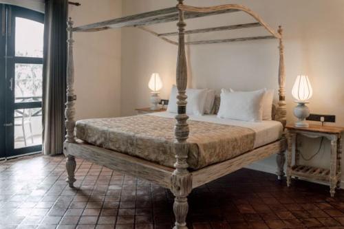 韦利格默Naomi Beach Resort - Adults only的一间卧室配有一张天蓬床和两盏灯。