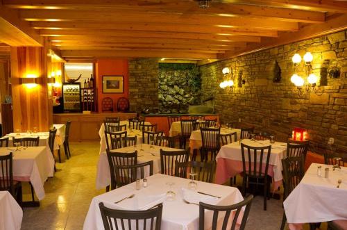 阿林萨尔HOTEL VICTORIA的一间设有白色桌椅的餐厅,拥有砖墙