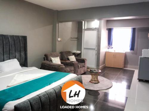 KikuyuLoaded homes的一间卧室配有一张床、一张沙发和一台电视。