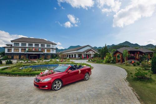 木州县Thao Nguyen Resort Moc Chau的停在房子前面的车道上的红色汽车