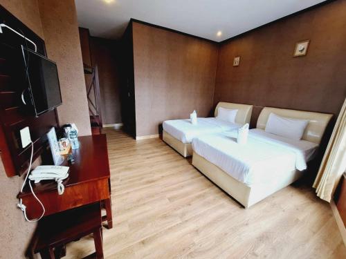 万象Sinakhone Vientiane Hotel的酒店客房设有两张床、一张桌子和一台电视。