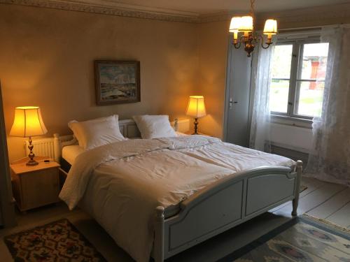MalingsboProfessorsvillan - hyr hela huset的一间卧室配有一张床、两盏灯和一个窗户。