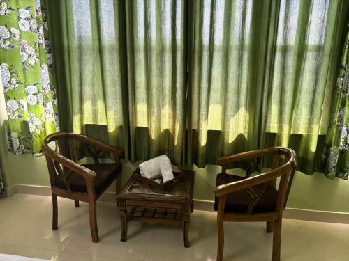 西姆拉Zu-Zu Hostels的窗帘前的两把椅子和一张桌子