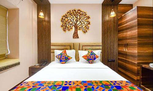 加尔各答FabHotel Jalsa Residency New Town的卧室配有一张床铺,墙上挂着一棵树