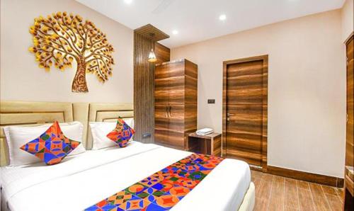 加尔各答FabHotel Jalsa Residency New Town的卧室配有一张大床,墙上挂着一棵树