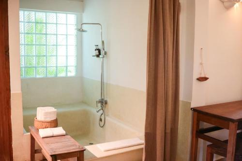 磅同省松博乡村酒店的带浴缸的浴室和窗户。