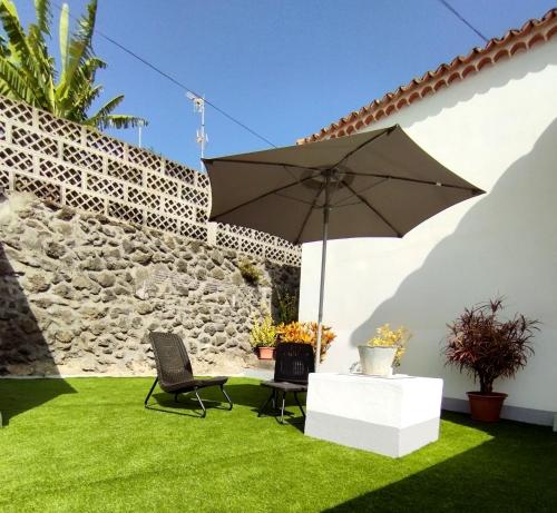 马佐La casa de Isabel的一个带遮阳伞和椅子的草地庭院