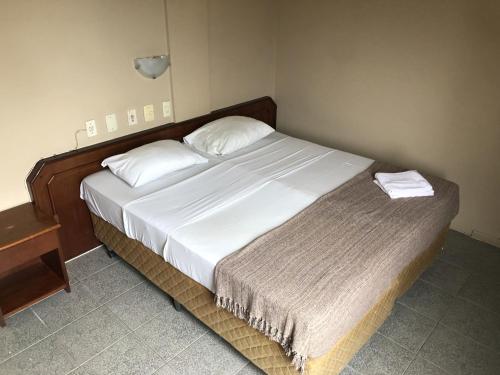 弗洛里亚诺波利斯HANNA Praia Hotel - Florianópolis的一间卧室配有一张带白色床单的大床