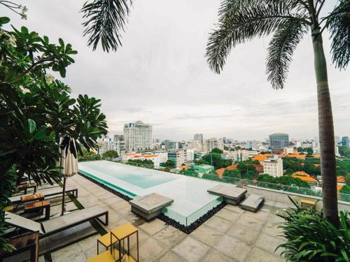 胡志明市Serenity Saigon Sky Villas的棕榈树建筑屋顶上的游泳池