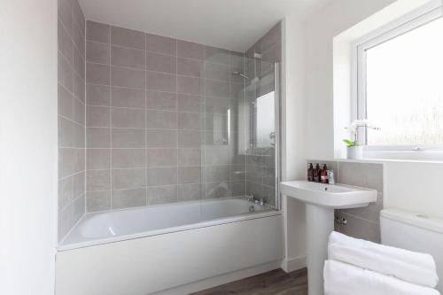 Stunning 4 Bed 3 Bathroom Home的白色的浴室设有浴缸和水槽。