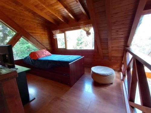拉安戈斯图拉镇Mutisia Puerto Manzano的小木屋内的卧室,配有一张床和凳子